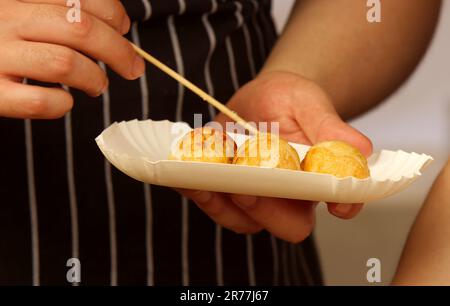 Cuisinez sur le stand de l'ambassade du Japon en collant une partie de boulettes frite dans une boîte en papier que le client peut emporter chez lui. Banque D'Images