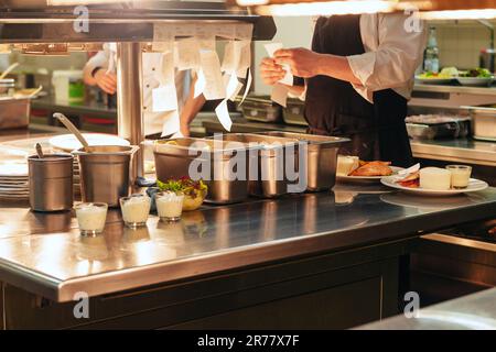 Commandes de nourriture sur la table de cuisine dans le restaurant, les ordres de lecture principaux et la cuisine dans la cuisine professionnelle de restaurant Banque D'Images