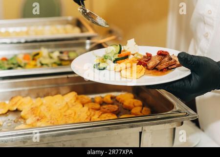 Plat principal restauration pour mariage ou fête, serveur servant les invités Banque D'Images