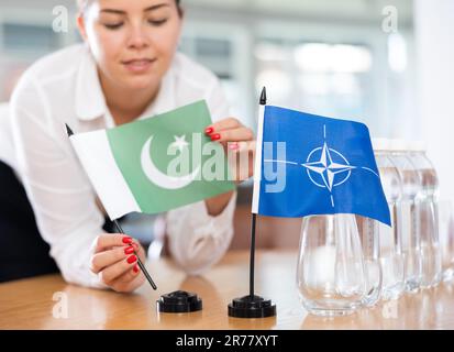 Femme d'affaires qui organise les drapeaux de l'OTAN (OTAN) et du Pakistan pour présentation et négociations Banque D'Images