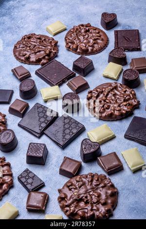 Variété de produits de chocolat photographiés en studio sur fond gris clair avec texture blanche. Chocolat noir, chocolat au lait, chocolat blanc, c Banque D'Images