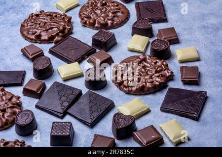 Variété de produits de chocolat photographiés en studio sur fond gris clair avec texture blanche. Chocolat noir, chocolat au lait, chocolat blanc, c Banque D'Images