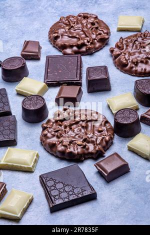 Variété de produits de chocolat photographiés en studio sur fond gris clair avec texture blanche. Chocolat noir, chocolat au lait, chocolat blanc, c Banque D'Images