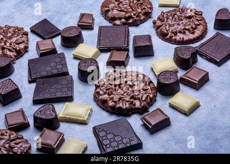 Variété de produits de chocolat photographiés en studio sur fond gris clair avec texture blanche. Chocolat noir, chocolat au lait, chocolat blanc, c Banque D'Images