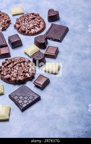 Variété de produits de chocolat photographiés en studio sur fond gris clair avec texture blanche. Chocolat noir, chocolat au lait, chocolat blanc, c Banque D'Images