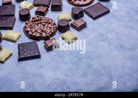 Variété de produits de chocolat photographiés en studio sur fond gris clair avec texture blanche. Chocolat noir, chocolat au lait, chocolat blanc, c Banque D'Images