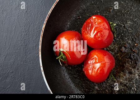 Tomates grillées frites dans une casserole noire sur une table en béton noir. vue de dessus avec espace de copie Banque D'Images