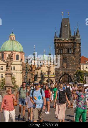 PRAGUE, RÉPUBLIQUE TCHÈQUE - touristes traversant le pont Charles. Tour du pont de la vieille ville à l'arrière. Banque D'Images