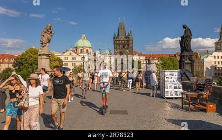 PRAGUE, RÉPUBLIQUE TCHÈQUE - touristes traversant le pont Charles, homme en scooter. Tour du pont de la vieille ville à l'arrière. Banque D'Images