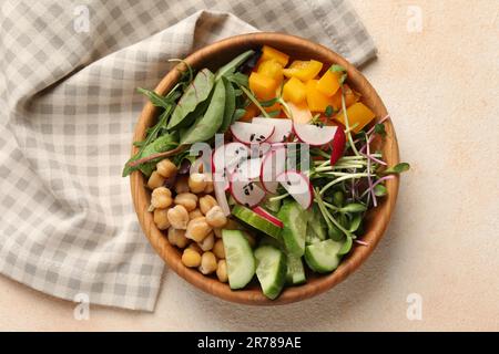 Délicieux bol végétalien avec concombres, pois chiches et radis sur table beige, vue du dessus Banque D'Images