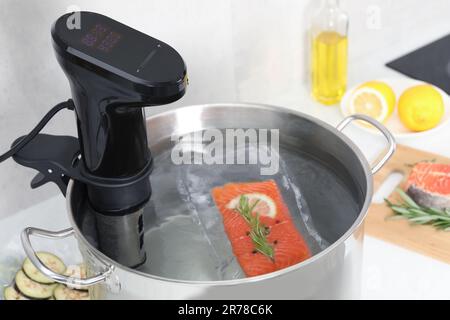 Sous vide cuisinière et saumon emballé sous vide dans une casserole sur table, gros plan. Circulateur à immersion thermique Banque D'Images