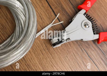 Pinces coupantes et câble avec fil dénudé sur table en bois, plat Banque D'Images