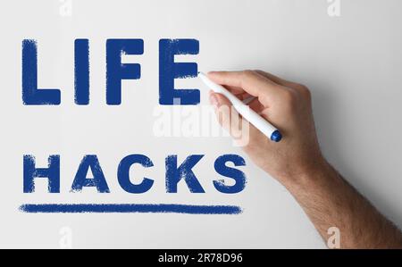 Homme écrivant des mots Life Hacks avec marqueur sur le tableau blanc, gros plan Banque D'Images