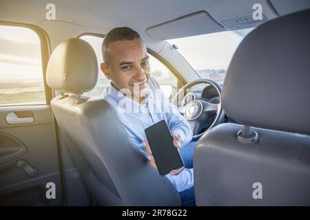 Le conducteur montre l'écran de son téléphone portable dans sa voiture avec un espace de copie. Banque D'Images