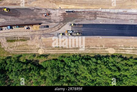 12 juin 2023, Saxe, Böhlen: Des travaux de construction sur le A72 près de Großdeuben coupent un andain dans des zones boisées. L'écart entre le A72 et le A38 devrait être comblé d'ici la mi-juillet. D'ici 2026, la plus grande partie de la nouvelle construction devrait être achevée et le trafic de la région de Vogtland à Leipzig pourra se déplacer sur deux voies sans interruption. La construction de la fermeture de l'écart est complexe parce que la route traverse les terrains de déversement d'une ancienne mine à ciel ouvert. (Photo aérienne avec drone) photo: Jan Woitas/dpa Banque D'Images