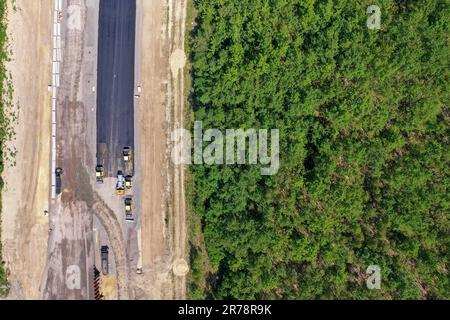 12 juin 2023, Saxe, Böhlen: Des travaux de construction sur le A72 près de Großdeuben coupent un andain dans des zones boisées. L'écart entre le A72 et le A38 devrait être comblé d'ici la mi-juillet. D'ici 2026, la plus grande partie de la nouvelle construction devrait être achevée et le trafic de la région de Vogtland à Leipzig pourra se déplacer sur deux voies sans interruption. La construction de la fermeture de l'écart est complexe parce que la route traverse les terrains de déversement d'une ancienne mine à ciel ouvert. (Photo aérienne avec drone) photo: Jan Woitas/dpa Banque D'Images