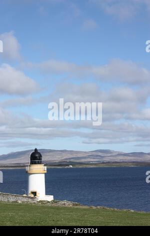 Vue sur le Loch Indaal vers l'autre partie de l'île d'Islay avec un mouton et un petit phare au premier plan Banque D'Images