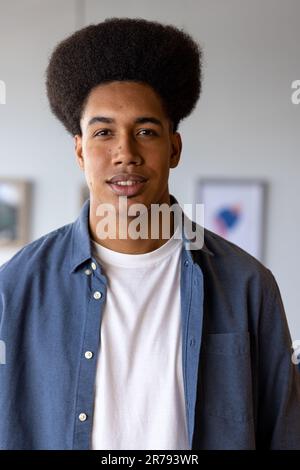Portrait d'homme d'affaires occasionnel biracial heureux avec afro souriant dans le bureau Banque D'Images