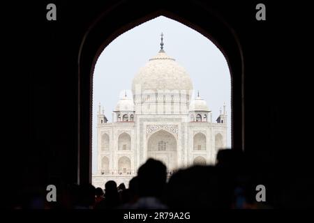 Arcade de la porte principale dans l'entrée du Taj Mahal avec des silhouettes de touristes, vue sur le mausolée de marbre Taj Mahal point de repère à travers l'arche, afflux massif de t Banque D'Images