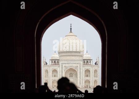 Arcade de la porte principale dans l'entrée du Taj Mahal avec des silhouettes de touristes, vue sur le mausolée de marbre Taj Mahal point de repère à travers l'arche, afflux massif de t Banque D'Images