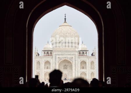 Arcade de la porte principale dans l'entrée du Taj Mahal avec des silhouettes de touristes, vue sur le mausolée de marbre Taj Mahal point de repère à travers l'arche, afflux massif de t Banque D'Images