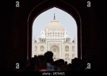 Arcade de la porte principale dans l'entrée du Taj Mahal avec des silhouettes de touristes, vue sur le mausolée de marbre Taj Mahal point de repère à travers l'arche, afflux massif de t Banque D'Images