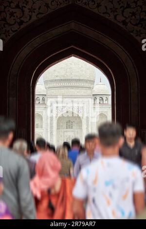 Arcade de la porte principale dans l'entrée du Taj Mahal avec des silhouettes de touristes, vue sur le mausolée de marbre Taj Mahal point de repère à travers l'arche, afflux massif de t Banque D'Images