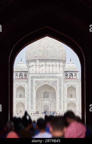 Arcade de la porte principale dans l'entrée du Taj Mahal avec des silhouettes de touristes, vue sur le mausolée de marbre Taj Mahal point de repère à travers l'arche, afflux massif de t Banque D'Images