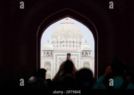 Arcade de la porte principale dans l'entrée du Taj Mahal avec des silhouettes de touristes, vue sur le mausolée de marbre Taj Mahal point de repère à travers l'arche, afflux massif de t Banque D'Images