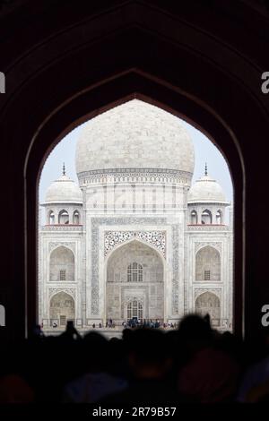 Arcade de la porte principale dans l'entrée du Taj Mahal avec des silhouettes de touristes, vue sur le mausolée de marbre Taj Mahal point de repère à travers l'arche, afflux massif de t Banque D'Images