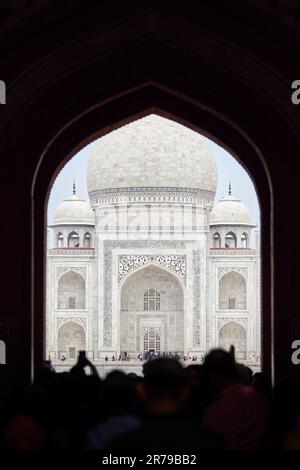 Arcade de la porte principale dans l'entrée du Taj Mahal avec des silhouettes de touristes, vue sur le mausolée de marbre Taj Mahal point de repère à travers l'arche, afflux massif de t Banque D'Images