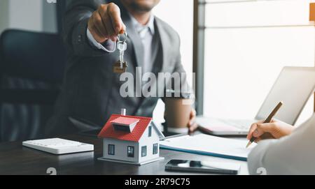 Vente à domicile et concept d'assurance à domicile. L'agent immobilier donne les clés de la maison à la femme et demande au client de signer les documents pour rendre le contrat légal Banque D'Images