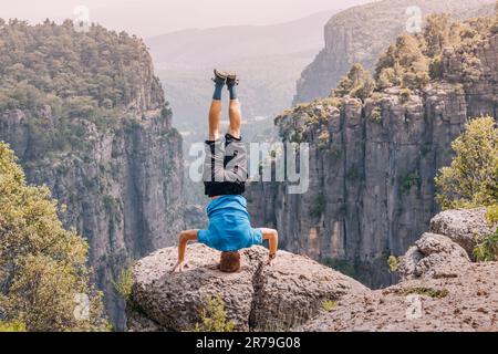 Homme debout sur sa tête au bord d'une grande falaise avec vue sur le canyon Tazi en Turquie. Concept de pose de yoga Banque D'Images