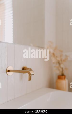 Une photo de l'intérieur d'une salle de bains moderne avec des éléments en porcelaine blanche contrastent avec les touches dorées Banque D'Images