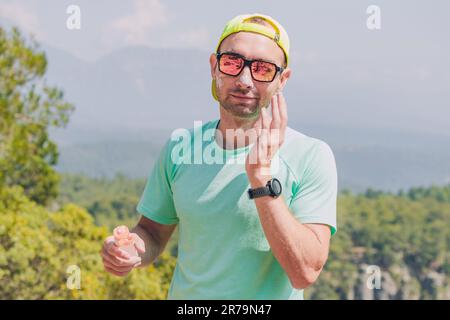 Randonneur sportif homme ski coureur de ciel appliquant la crème solaire pour protéger la peau des rayons UV dangereux de soleil hauts dans les montagnes. Concept de santé de voyage Banque D'Images