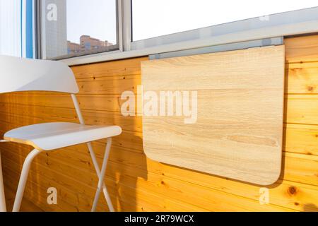 table pliante en position fermée sur le balcon. table pliante en bois fixée au mur. table pliante sur le balcon. table et chaises sur le bal Banque D'Images