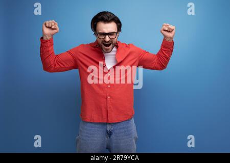 joyeux homme millénaire brunette de 35 ans avec des cheveux magnifiques dans une chemise rouge Banque D'Images