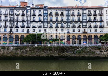 Fleuve Nervion et bâtiment blanc coloré avec balcons bleus et toit en tuiles rouges sur Martzana Kaia / Muelle de Marzana. Pays basque, Espagne. Banque D'Images