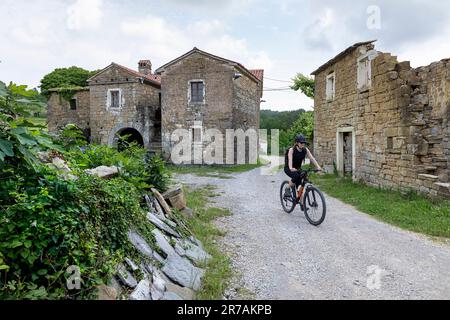 Femme touriste, cycliste sur un voyage à vélo autour de la péninsule d'Istrie en Slovénie, vélo à travers Abitanti, village traditionnel de pierre d'istrie, slovénie Banque D'Images