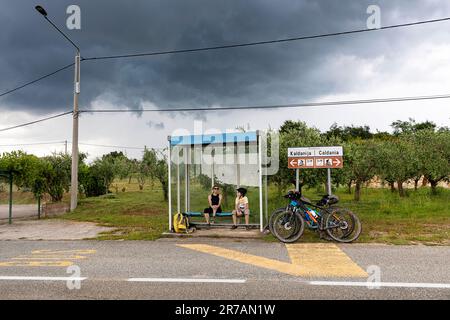 Touristes, cyclistes, mère et fils en VTT près de Buje dans la péninsule d'Istrie, attendant que la pluie s'arrête sous le toit d'une gare routière, Croatie Banque D'Images