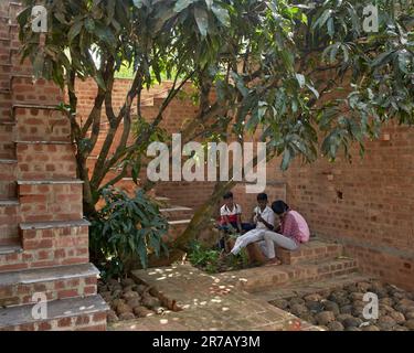 Vue à travers les arches avec les enfants dans l'atelier d'art. Ruines sous-tériennes, Kaggalipura, Bangalore, Inde. Architecte : un seuil Architectes, 2023. Banque D'Images