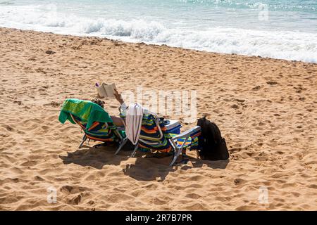 Une femme lisant sur une plage de Los Angeles, Californie, avec des vagues qui s'écrasent sur le sable à proximité Banque D'Images