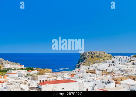 Vue sur le toit de la ville de Lindos et de la mer émeraude avec des bateaux passant, île de Rhodes, îles grecques de l'archipel Dodécanèse, Europe. Vacatio Banque D'Images