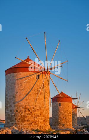 Cadre vertical sur les anciens moulins à vent de la baie au coucher du soleil, dans la ville de Rhodes sur l'île de Rhodes de l'île de l'archipel Dodécanèse Banque D'Images