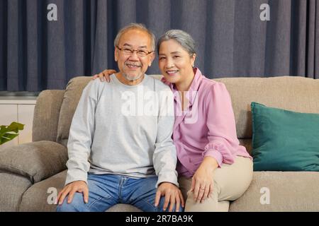 Portrait d'un couple senior souriant à l'appareil photo et reposant à la maison Banque D'Images