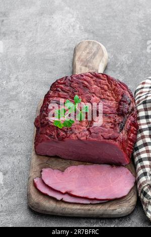 Viande de bœuf séchée en tranches saccadées sur fond gris Banque D'Images