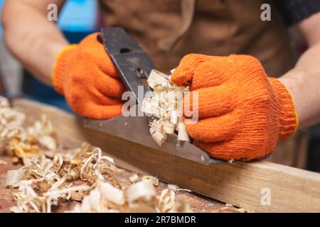 Les mains de Carpenter plantant une planche de bois avec un plan de main, lieu de travail Banque D'Images