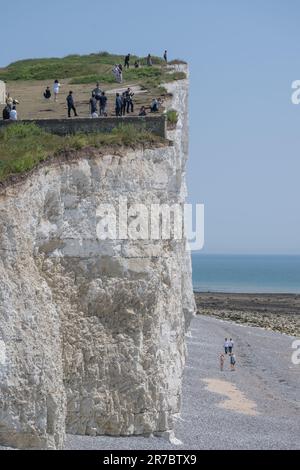 Touristes se tenant dangereusement près de Beachy Head Cliff Edge vu de Burning Gap, East Sussex. Ces dangereuses falaises de craie s'effondrent régulièrement Banque D'Images