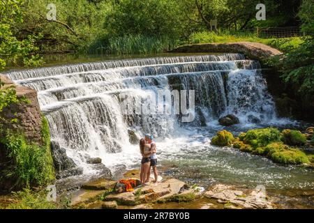 Un jeune couple a embrassé et embrassé sous une cascade sur la rivière Wye dans le district de Monsall Dale Peak Derbyshire pendant la vague de chaleur de 2023 Banque D'Images