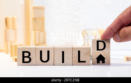 Temps de reconstruction du symbole. A tourné des cubes en bois et change le mot « construire » en « construire ». Belle table grise, fond bleu. Affaires, construire ou rebui Banque D'Images